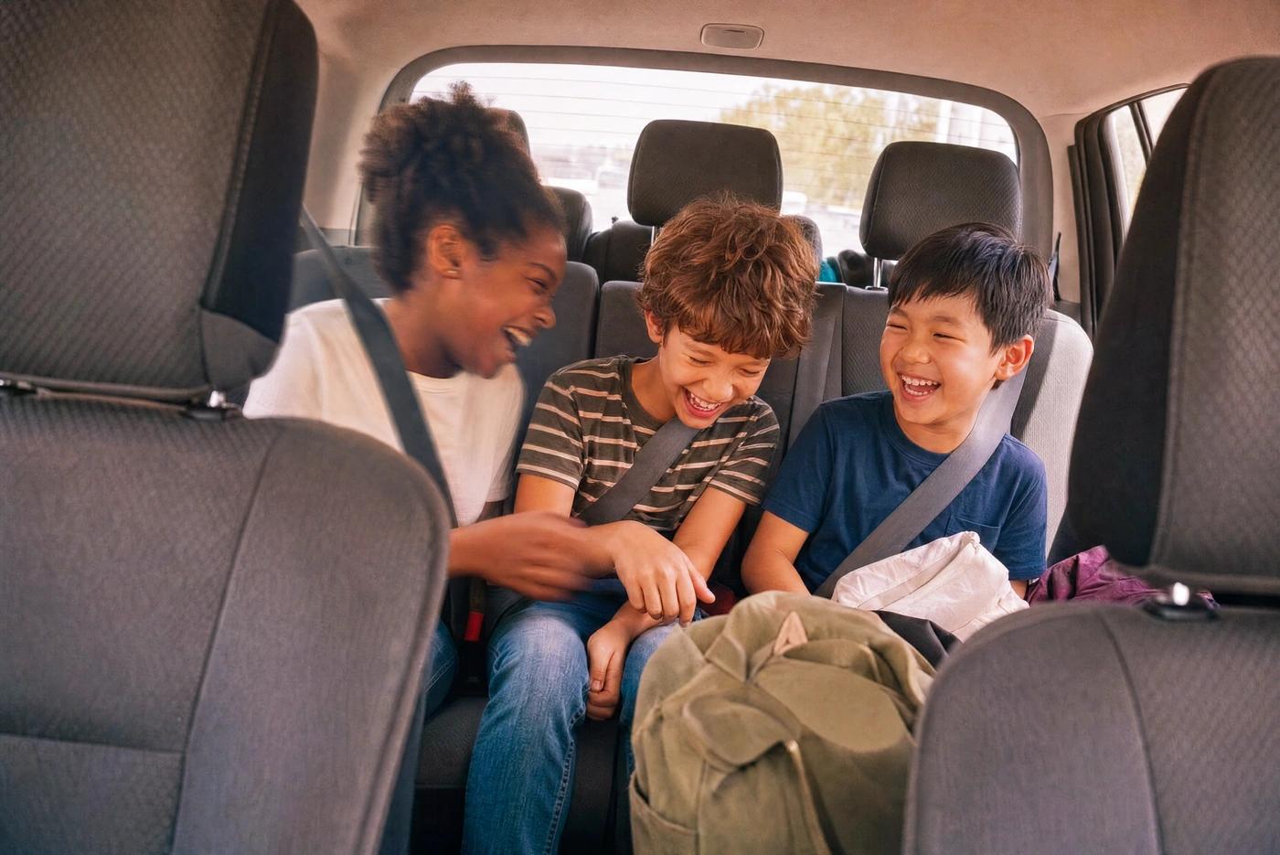 Three children laughing in the back seat of a car